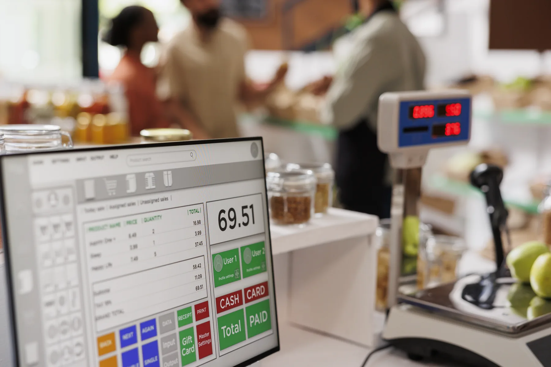 A shopkeeper serving customers at an OptiBiz point-of-sale counter